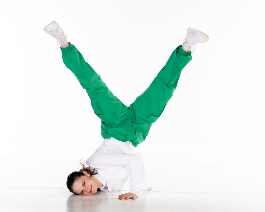 girl in white and green pants posing while feet up the air