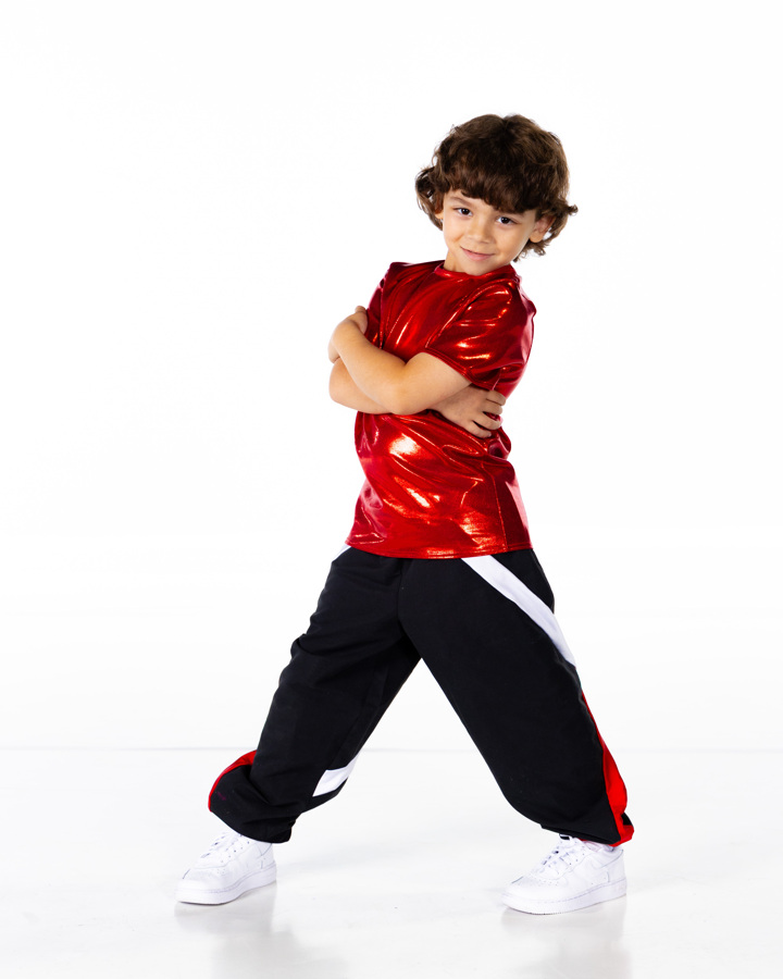 young kid in red and black pants posing arms crossed and legs apart